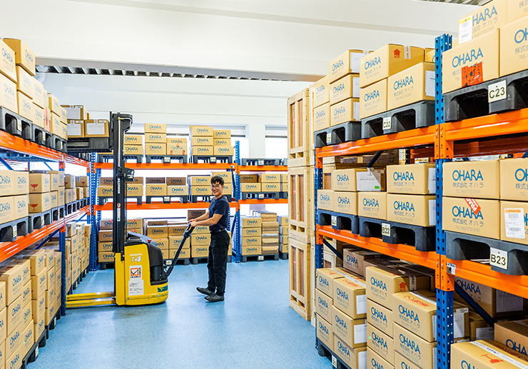 In the picture there is a man with a pallet truck in a warehouse.